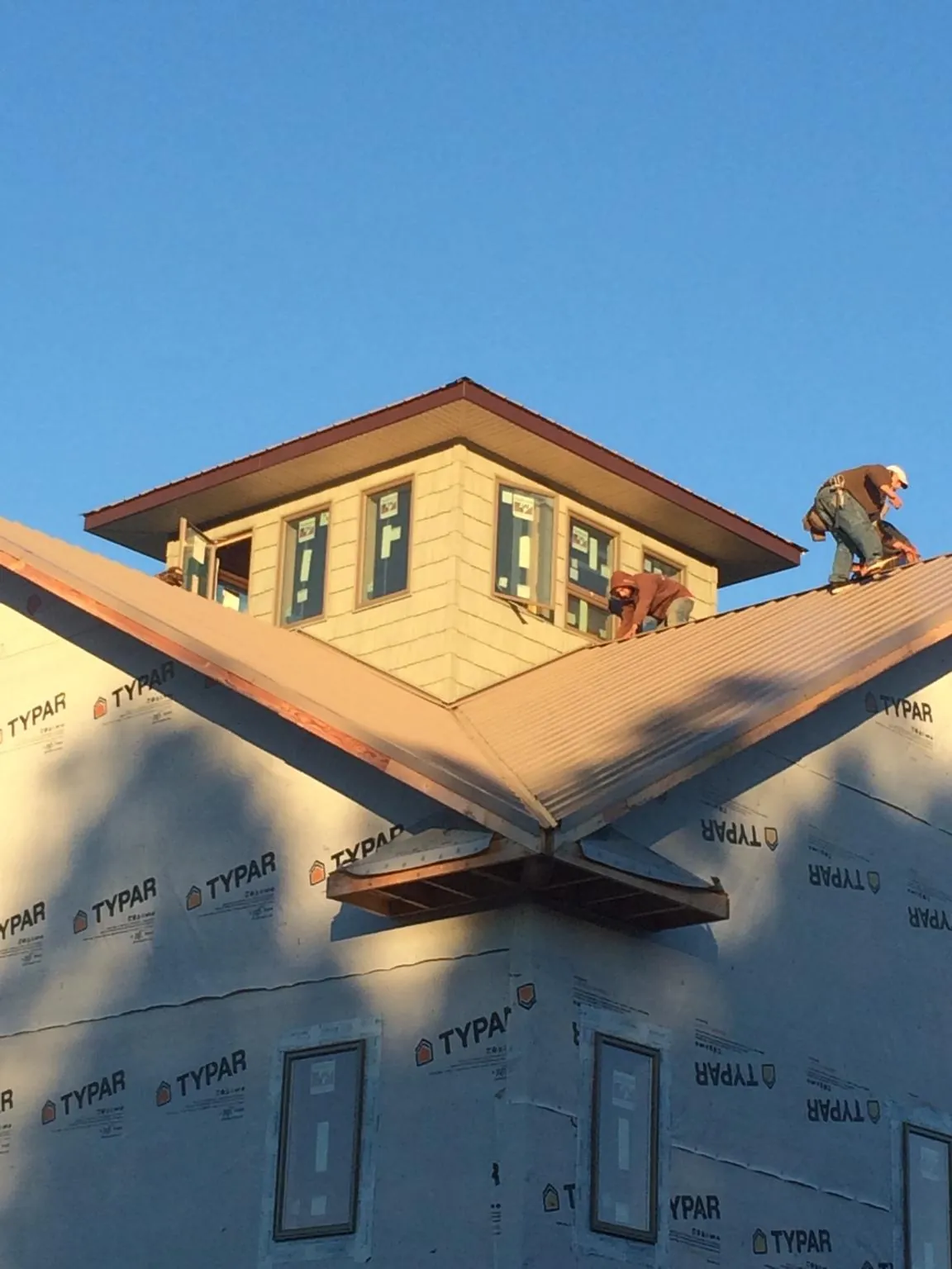 Roofers working around a rooftop cupola on a new metal roof at sunset — Roof Waterproofing in Bowman by Roofing Brothers